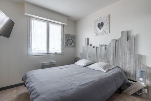 um quarto com uma cama grande e uma cabeceira em madeira em Appartement dos à la marina - Proche de la plage em Courseulles-sur-Mer