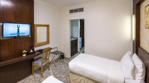 a hotel room with a bed and a desk and a television at Jiwar Al Madina Hotel in Al Madinah