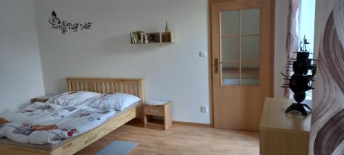 a bedroom with a bed with white sheets and a door at Apartmán v Ladově kraji in Ondřejov