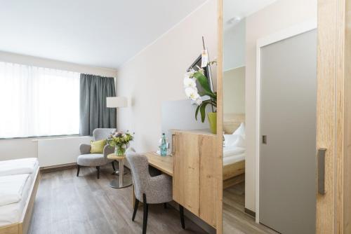 a hotel room with a desk and a bedroom at Hotel Forsthaus Grüna Betreibergesellschaft mbH in Chemnitz
