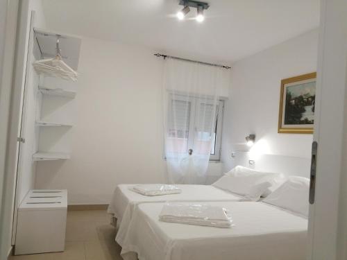 a white bedroom with two beds and a window at Villa Laura Residence Hotel Apartments & Studios in Ascea