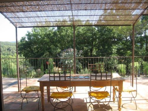 una mesa de madera y sillas en un patio en Grande Maison Mitoyenne & Spa à Bulles au Soleil dans Quartier Calme !, en Entrecasteaux