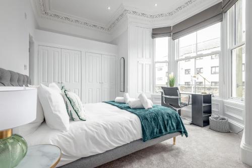 a white bedroom with a bed and a chair at Skye Sands - Swilken Garden Residence - St Andrews in St. Andrews