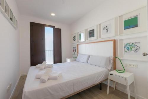 a bedroom with a white bed with two towels on it at Apartamentos Mercado Central in Valencia