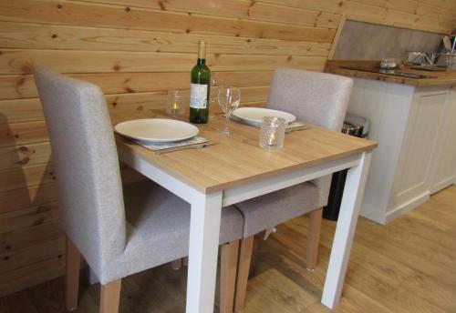 a wooden table with two chairs and a bottle of wine at Harlosh Hideaways - Aurora Pod in Harlosh