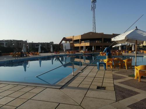 una piscina con sillas, mesas y sombrilla en 52H Green leaves Village, families & couples only, en Dawwār Abū Duray‘ah ‘Abd al Karīm