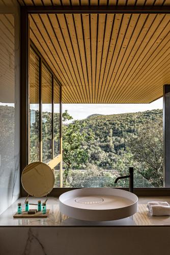 a bathroom with a round tub in front of a large window at Souki ~ Lodges & Spa in Cabrières