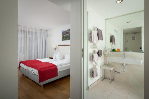 a bedroom with a bed and a bathroom with a sink at Hotel & Restaurant Dankl in Lofer
