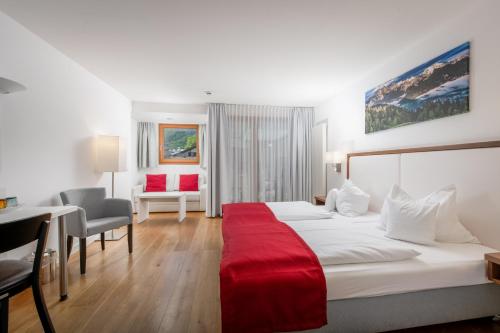 a hotel room with a large bed with a red blanket at Hotel & Restaurant Dankl in Lofer