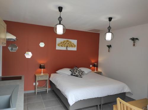 Schlafzimmer mit einem weißen Bett und orangefarbenen Wänden in der Unterkunft Studio Les chambres de la source - Tadorne in Sancourt