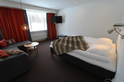 a bedroom with a bed and a couch and a window at STF Hemavans Fjällcenter in Hemavan