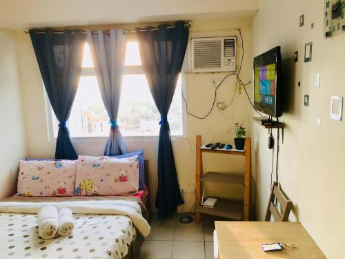 a bedroom with a bed with blue curtains and a window at Booker Com in Mandaluyong in Manila