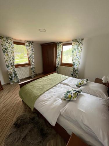 a bedroom with a large bed and two windows at Penzión U dvoch levov in Oravský Podzámok