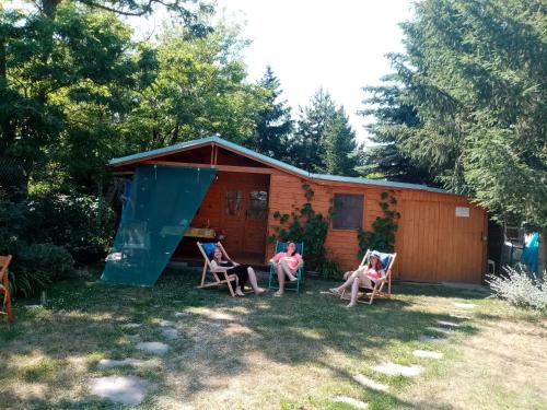 three people sitting in chairs in front of a cabin at Penzion Slunce nad Vinným Sklepem in Moravská Nová Ves