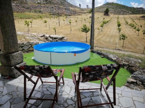 2 chaises assises sur une terrasse avec piscine dans l'établissement Quinta do Chãozinho, à Alijó