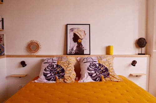 een slaapkamer met een bed met kussens en een foto bij Studio Hévéa, expérience de standing à la marina in Saint-François