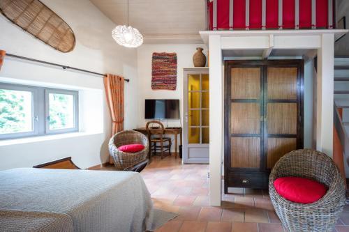 una camera con un letto e due sedie con cuscini rossi di Le Mas De Ribard a Bréau-et-Salagosse