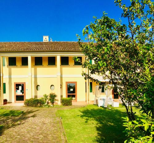 a large yellow house with a lawn in front of it at Il Paradello Albergo in Porto Levante