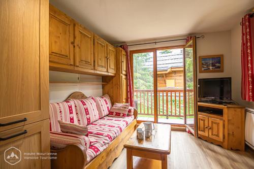 ein Wohnzimmer mit einem Sofa und einem TV in der Unterkunft Chalets D'Arrondaz in Valfréjus