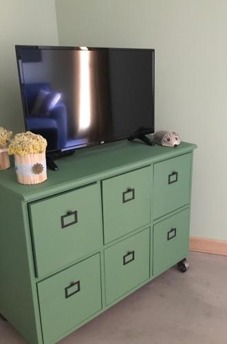 a green dresser with a television on top of it at Côté Nuit in Capestang