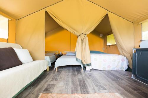 a room with a couch and a bed in a tent at Terre d'Horizon Auvergne in Chastreix