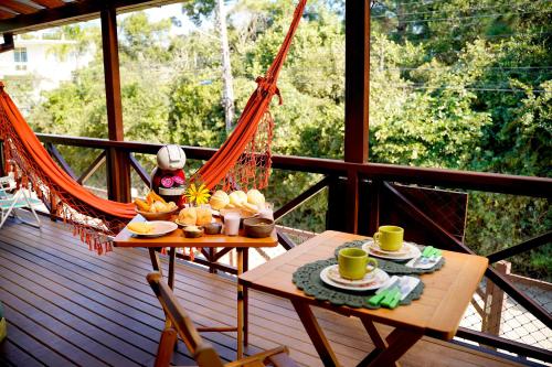 a porch with a hammock and two tables with coffee cups at Morada dos Prass in Guarda do Embaú
