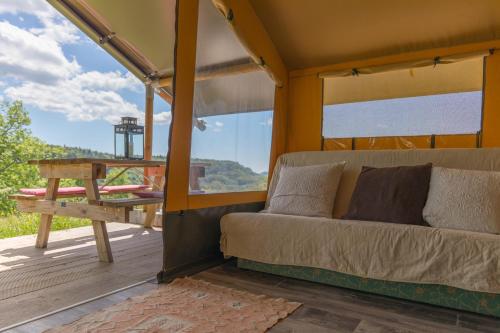 a couch on a porch with a table and a view at Terre d'Horizon Auvergne in Chastreix