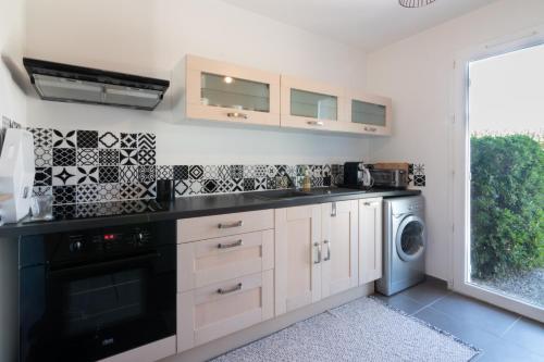 une cuisine avec lave-linge et sèche-linge à côté d'une fenêtre dans l'établissement L'Isle Ô Jardin, à LʼIsle-sur-la-Sorgue