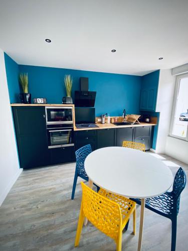 une cuisine avec une table blanche et deux chaises dans l'établissement Gîte « Au bord des Embruns », à Grandcamp-Maisy