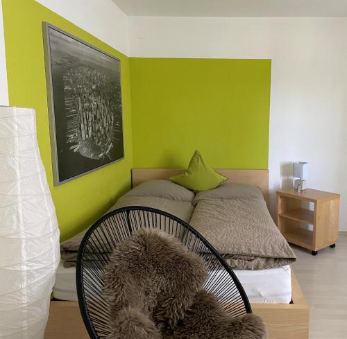ein Schlafzimmer mit einem Bett mit grünen Wänden und einem Stuhl in der Unterkunft Black Forest Guest Stay in Pfalzgrafenweiler