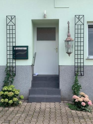 a white door on a house with flowers and a light at landpension-dette in Berlingerode