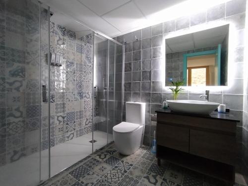 Un baño con inodoro, lavabo y espejo. en Casas del Castillo Peñíscola-Intramuros Suites, en Peñíscola