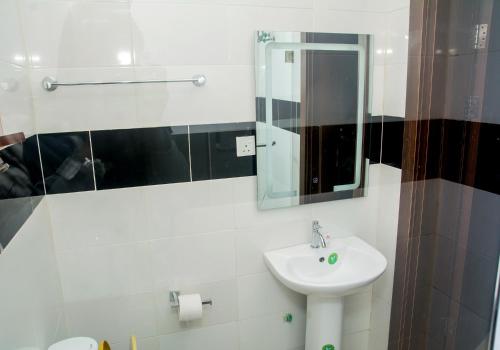 a white bathroom with a sink and a mirror at Presken Residence Annex in Ikeja