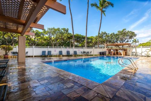 a swimming pool with a patio and palm trees at Aloha Kahakai in Wailea