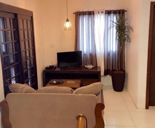 een woonkamer met een bank en een tafel met een tv bij Flat Deluxe Gramado in Gramado