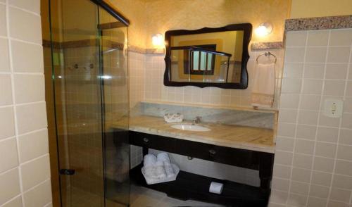 a bathroom with a sink and a shower with a mirror at Privillage Praia Pousada de Charme in Arraial d'Ajuda