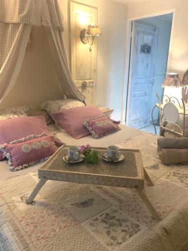 a bedroom with a bed with a table and two cups at La Porte Bleue : Guest house Cosy & Jaccuzi in Saint-Pierre