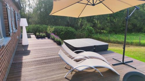 een patio met een tafel en stoelen en een parasol bij Villa ADurbuy avec Jacuzzi in Durbuy
