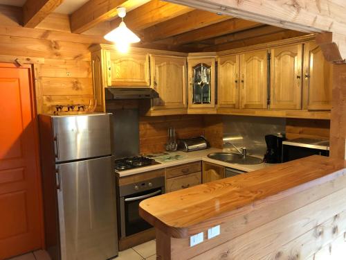 eine Küche mit Holzschränken und einem Kühlschrank aus Edelstahl in der Unterkunft CHALET 10 COUCHAGES EN HAUTE SAVOIE in La Chapelle-dʼAbondance