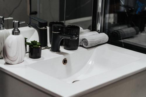 a bathroom sink with a black faucet and a mirror at Dudok House in Žilina