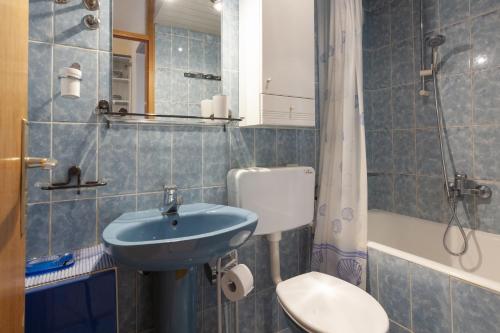 a blue tiled bathroom with a sink and a toilet at Villa Ban in Podgora