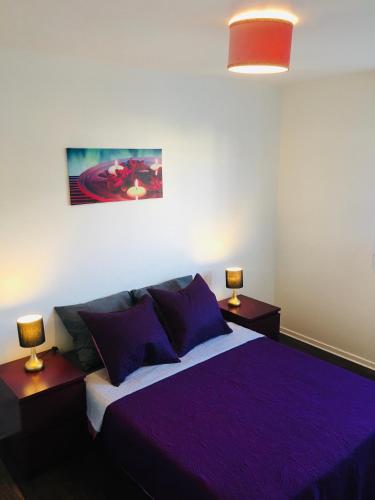 une chambre avec un lit violet avec deux lampes dans l'établissement Superbe Appartement lumineux proche Disney, à Montévrain