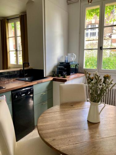 une cuisine avec une table avec un vase de fleurs dessus dans l'établissement Logis « Henriette » • Maison du XVe siècle, à Provins
