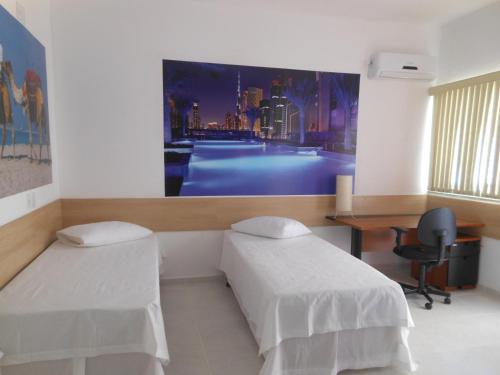 a room with two beds and a desk and a monitor at Pousada Dubai in Taubaté
