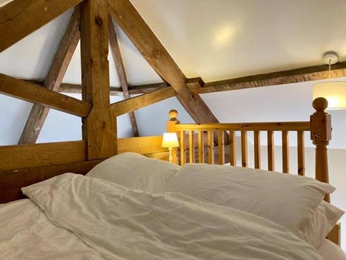 a bed with white sheets in a room with wooden beams at Brecks Cottage in Newark-on-Trent