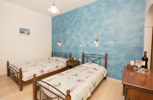 two beds in a room with a blue wall at Villa Pelekanos in Karterados