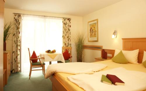 a bedroom with two beds and a table and a window at Apart-Hotel Pension Roßmayer in Bad Füssing