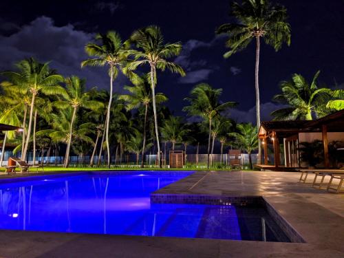 a pool at night with palm trees in the background at Casa Mia Pousada in Cabedelo