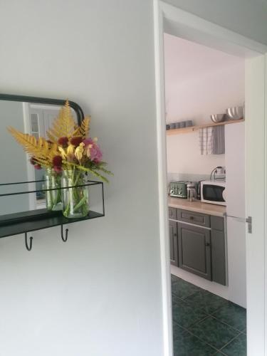 a kitchen with a vase of flowers on a shelf at Harbourside House Glengarriff in Glengarriff