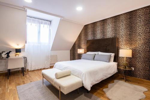 a bedroom with a large white bed and a chair at DE LA GUARDIA SUITE ROSAL in Oviedo